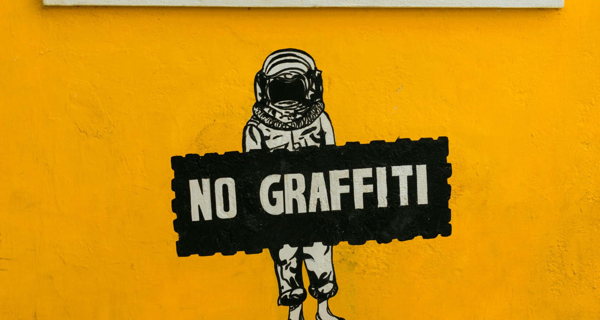 kein-graffiti-schild-an-gelb-gestrichener-wand-VrWyKyITBQs