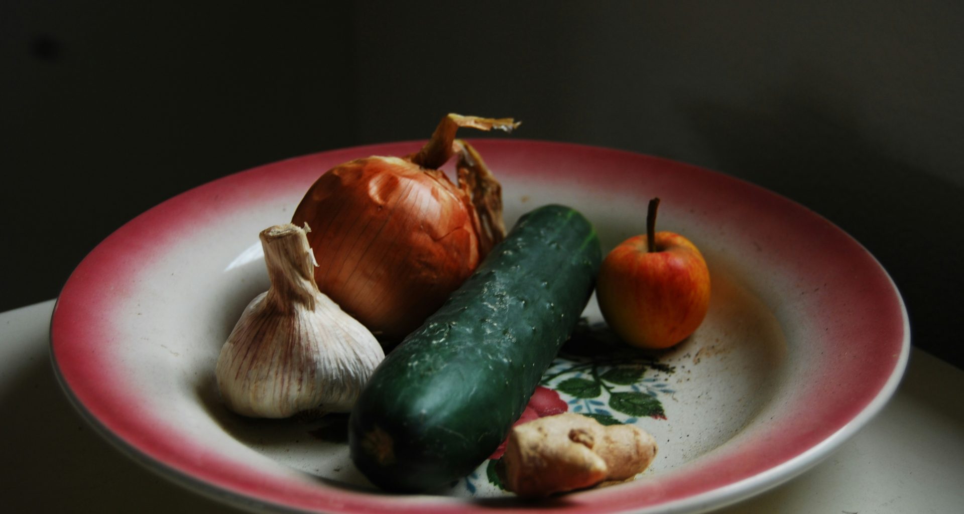 zwiebeln-knoblauch-ingwer-und-grunes-gemuse-auf-rundem-weissem-und-rotem-teller-VOE-n32iZf0