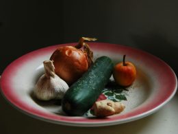 zwiebeln-knoblauch-ingwer-und-grunes-gemuse-auf-rundem-weissem-und-rotem-teller-VOE-n32iZf0