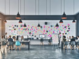 Team einer modernen Online-Marketing-Agentur arbeitet in offenen, hellen Räumen mit Whiteboards, Post-its und Flipchart an kreativen Strategien.