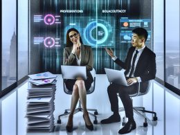 Berater zeigt auf ein Diagramm am Laptop, während ein Geschäftspartner von Präsentationsdokumenten umgeben ist; im Hintergrund verschwimmen reale Analysedaten.