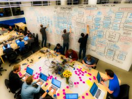 Technikaffines Team im Startup-Office arbeitet konzentriert an Directus-Architekturdiagrammen, Whiteboards voller Datenbankmodelle und API-Strategien sowie digitalen Tools und Monitoren.