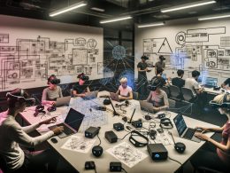 Ingenieur:innen entwickeln in einem modernen Labor mit Mixed-Reality-Headsets, Sensoren, Laptops, holografischen Overlays und User-Journey-Skizzen innovative Spatial-Computing-Prototypen.