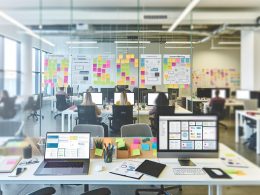 Modernes Großraumbüro mit motiviertem, vielfältigem Content-Team, das an Laptops und Monitoren arbeitet. Glaswand mit Post-its und strukturierter Content-Strategie, digitale Workflows auf Screens sichtbar.