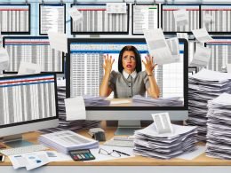 Chaotisch überladener Büroschreibtisch mit Papieren, Preislisten, mehreren Monitoren voller Excel-Tabellen und gestressten Marketingkollegen in einem modernen Büro.