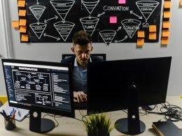 Ein Unternehmer sitzt vor mehreren Monitoren an einem modernen Arbeitsplatz. Die Bildschirme zeigen komplexe Workflows, Notion-Dashboard und API-Dokumentationen. Die Umgebung wirkt kreativ-chaotisch mit technischen Notizen und Startup-Flair.