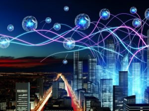Futuristische Skyline bei Sonnenuntergang mit Neon-Quantendaten als Lichtbänder und schwebenden, kristallinen Qubit-Knoten über den Glasgebäuden.