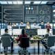 Moderne Büroumgebung mit jungen Data-Analysten, mehreren Bildschirmen mit Code, Dashboards, ETL-Pipelines und Datenvisualisierungen, unterstützt von digitalen Whiteboards.
