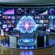 Futuristischer Arbeitsplatz eines Digital Marketers mit mehreren Monitoren, KI-Hologramm, leuchtenden Analytics-Charts und Social Media Elementen im Raum.