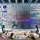 Team aus Marketers und Data Analysts im modernen Büro vor überladener Glaswand mit Daten, im Vordergrund klare Übersicht am Reporting-Board