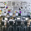 Modernes Büro mit kreativem Team, das Wireframes, SEO-Reports und Webdesign-Layouts am großen Tisch bespricht. Laptops zeigen bunte Entwürfe und Analyse-Tools, während ein Whiteboard Skizzen und Diagramme zur Verbindung von Design und SEO präsentiert.