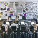 Modernes Büro mit kreativem Team, das Wireframes, SEO-Reports und Webdesign-Layouts am großen Tisch bespricht. Laptops zeigen bunte Entwürfe und Analyse-Tools, während ein Whiteboard Skizzen und Diagramme zur Verbindung von Design und SEO präsentiert.