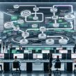 Futuristischer Büroraum mit riesiger transparenter Leinwand, die ein Automation-Flowchart zeigt. Im Hintergrund Marketer an Workstations mit digitalen Dashboards und Echtzeit-Performance-Grafiken.