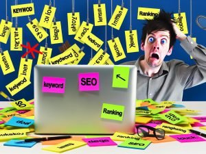 Moderner Redakteur am chaotischen Schreibtisch mit aufgeschlagenem Laptop, SEO-Notizzetteln und kreativem Redaktions-Alltag