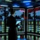 Futuristischer IT-Kontrollraum im Halbdunkel mit moderner Person vor Monitoren, die Cybersicherheits-Bedrohungen und Warnhinweise anzeigen. Verschwommene Serverracks und digitale Linien im Hintergrund erzeugen eine angespannte Atmosphäre.