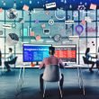 Marketer an Schreibtisch mit zwei Bildschirmen, Quora-Dashboard, nativer Anzeige im Quora-Feed, Sticky Notes zu Storytelling, Targeting und Performance, Kollegen im modernen Office-Hintergrund
