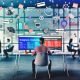 Marketer an Schreibtisch mit zwei Bildschirmen, Quora-Dashboard, nativer Anzeige im Quora-Feed, Sticky Notes zu Storytelling, Targeting und Performance, Kollegen im modernen Office-Hintergrund