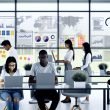 Junges, diverses Team von SEO-Spezialisten arbeitet konzentriert an Laptops vor Monitoren mit SEO-Daten und Traffic-Kurven in einem modernen, hellen Büro mit Glaswand und Notizzetteln.