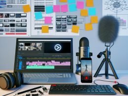 Aufgeräumter Schreibtisch eines TikTok-Creators mit Laptop, Mikrofon, Smartphone auf Stativ, Monitor mit Videobearbeitungsoftware, Kopfhörern und Storyboard-Zeichnungen im Hintergrund.