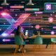 Social-Media-Manager tippt im modernen Co-Working-Space einen Prompt in ein KI-Interface, umgeben von visualisierten Datenströmen, Algorithmen und Social-Media-Symbolen.
