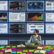 Digitalstratege arbeitet in modernem Newsroom mit Monitoren voller YouTube-Analytics, SEO-Diagrammen und Keyword-Recherche-Tools. Auf dem Tisch liegen Notizbücher, Laptop und bunte Post-its mit Content-Ideen.