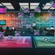 Modernes, helles Büro mit digital vernetzten Dashboards, diversen IT-Profis, Sicherheits- und Compliance-Symbolen sowie Illustrationen zu Schatten-IT und Datensilos.