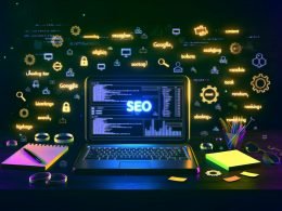 Aufgeklappter Laptop auf dunklem Schreibtisch mit SEO-Dashboard, Diagrammen und fliegenden Analyse-Icons, Neon-Akzente und leuchtende Schlagwörter im Nachthintergrund.