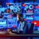 Illustration eines YouTubers vor Monitoren mit SEO-Daten, Metadaten-Icons wie Titel-Tags, Playlists, Thumbnails und SRT-Dateien in modernem Technik-Büro.