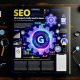 Dramatisches Magazin-Doppelseitenlayout mit großem Google-Algorithmus-Zahnrad, umgeben von SEO-relevanten Icons und neonleuchtenden Begriffen wie Ranking, Technik und User Experience auf dunklem Hintergrund.