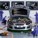 Moderne Werkstatt mit offenem Ferrari-Motorraum voller Website-Komponenten, umgeben von SEO-Experten mit Laptops und technischen Monitoren.