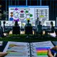 Modernes Büro bei Nacht mit mehreren Menschen in angespannter Gruppendiskussion vor großer Bildschirmfläche, die komplexe Website-Architektur und SEO-Daten zeigt. Im Vordergrund ein SEO-Notizblock, im Hintergrund Monitore mit Tools wie Screaming Frog.