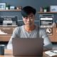 Junge Bloggerin im modernen Home-Office am Laptop mit Blog-Dashboard, Analytics-Statistiken und Monetarisierungsmodellen auf dem Bildschirm, Kaffetasse und Technik im Hintergrund.