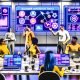 SEO-Team analysiert bunte Dashboards und Blogger Outreach Tools im modernen deutschen Workspace mit Logos von Pitchbox, BuzzStream und NinjaOutreach, umgeben von Technologie-Trends 2025.