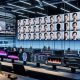 Eleganter, moderner Arbeitsplatz mit großen Monitoren, auf denen ein Team von Videocreators an KI‑Lippensynchronisation arbeitet: Wellenform‑Audio, Phonem‑zu‑Visem‑Diagramme und Zeitachsen für realistische Mundanimationen; im Hintergrund wechselt das Gesicht eines Sprechers nahtlos zwischen Sprachen mit perfekter Lippensynchronität, kleinere Screens zeigen 3D‑Gesichts‑Rigs, neuronale Netzdiagramme und LSE‑D‑Metriken; Overlays für digitale Wasserzeichen, Einwilligungs‑Checklisten und Compliance‑Siegel.