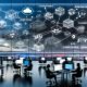 Hightech-Arbeitsplatz mit Team an Monitoren und digitalen Dashboards; Flowchart zeigt modulare KI-Bausteine (Prompt Chains, Agents, RAG, Evaluation), Datenströme zwischen On-Premise und Cloud, Guardrails für SEO/Ads/E-Mail und Compliance, Vektor-Datenbanken, ETL, A/B-Tests; Kobold-Maskottchen leuchtet den Weg aus veralteten Tabellen und Folien.