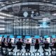 Modernes KI-Forschungsinstitut mit Teams an großen Workstations, Modellvisualisierungen, transparenten Datenflüssen, Serverracks, Robotik, HPC und Governance.