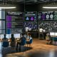 Moderner digitaler Marketing-Kontrollraum mit großen Echtzeit-Dashboards; Expertin trainiert ein ML-Modell in Python (Logistic Regression), anderer passt Kampagnen per API an mit Einwilligungs-Hinweisen; Whiteboard von Tracking bis Umsatz; GDPR/DSGVO- und ethische KI-Icons; Side-Screen mit 90‑Tage‑Roadmap und Tools wie BigQuery, dbt, Kafka.