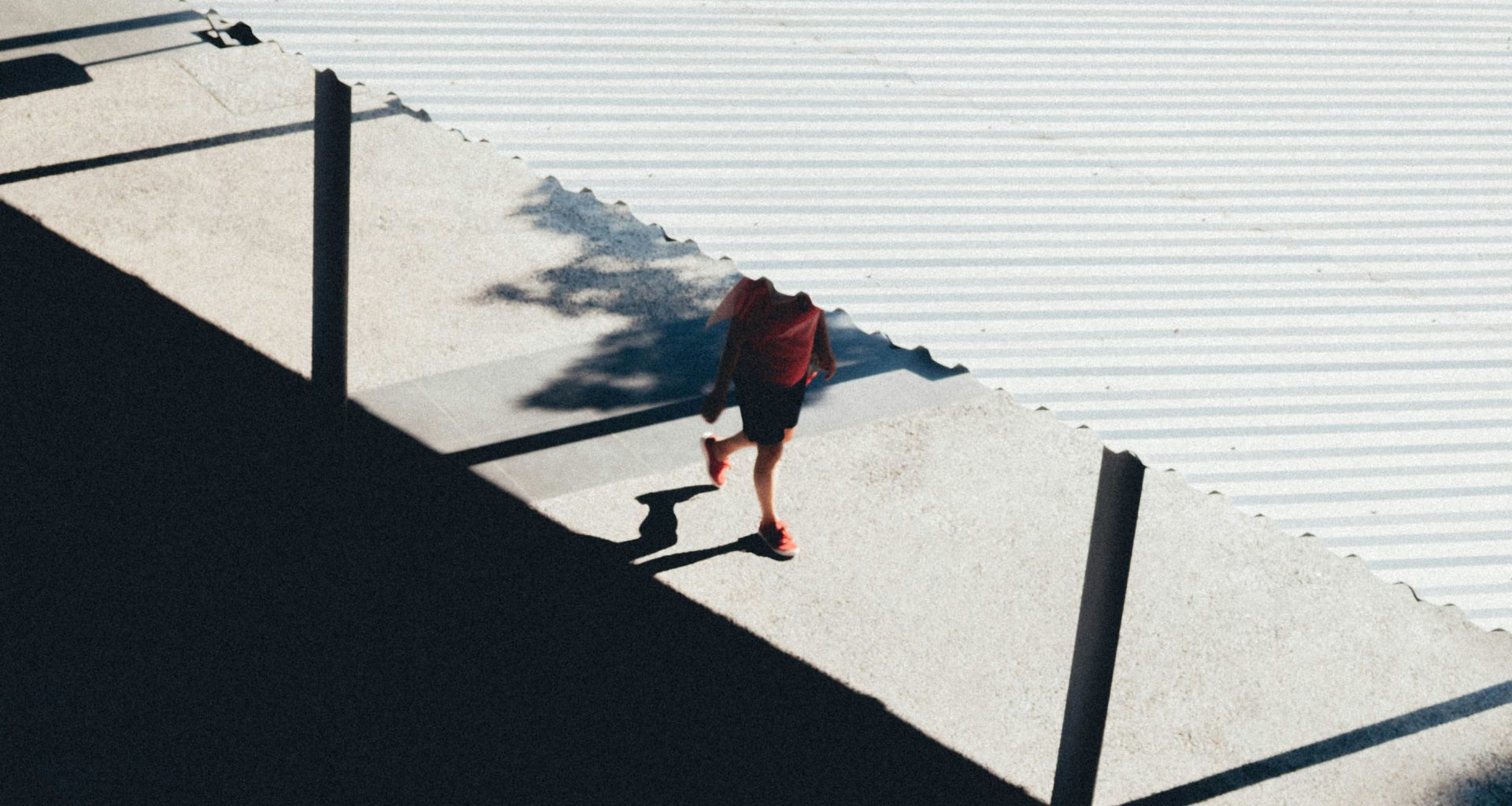 person-in-roter-jacke-und-schwarzer-hose-geht-auf-grauem-betonpflaster-in-der-nahe-eines-gewassers-COYUdbaaeQ8