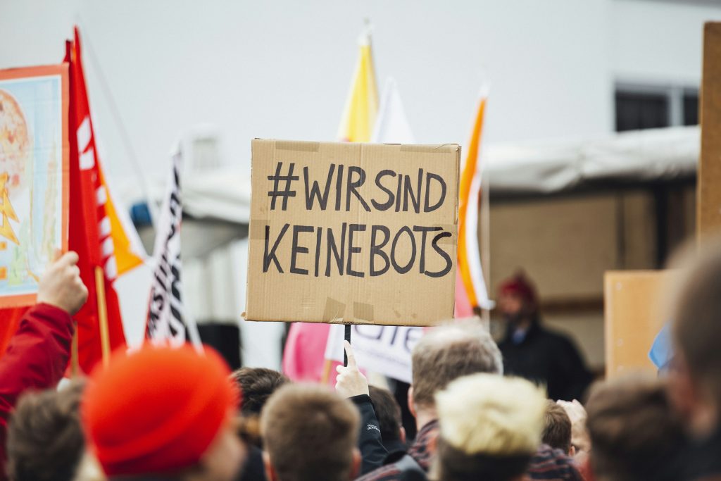 person-raising-wirsind-keinebots-signboard-4UTVClfWuEw