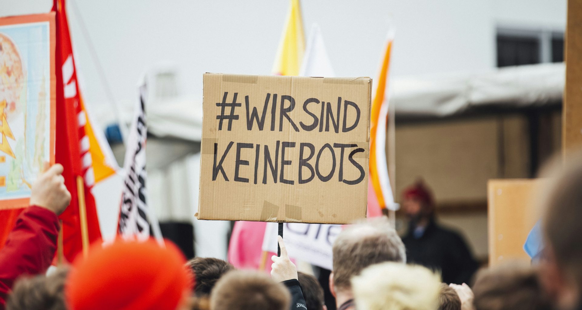 person-raising-wirsind-keinebots-signboard-4UTVClfWuEw