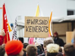 person-raising-wirsind-keinebots-signboard-4UTVClfWuEw