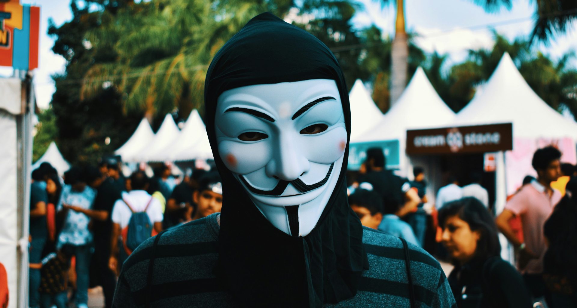person-die-tagsuber-eine-guy-fawkes-maske-in-der-nahe-von-menschen-tragt-wK3WaYrHEBM