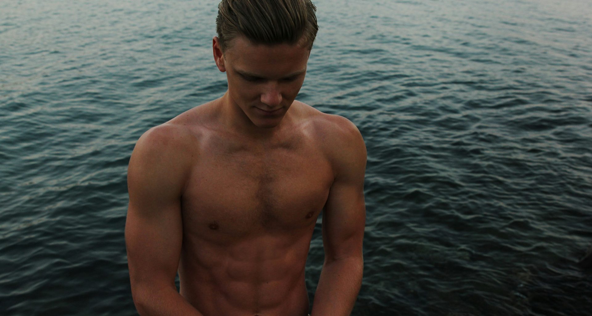 oben-ohne-mann-schaut-mit-ozeanhintergrund-hinunter-BMogzCQYfb4