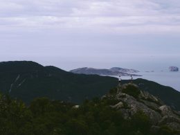 zwei-manner-stehen-auf-dem-gipfel-eines-berges-in-der-nahe-des-meeres-Lq-3swjHIl4