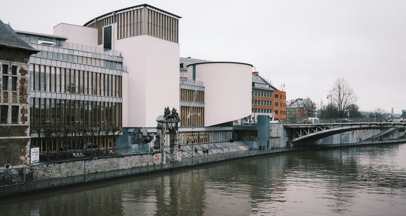 weisses-betongebaude-in-der-nahe-des-flusses-tagsuber--LACmV1rhyg