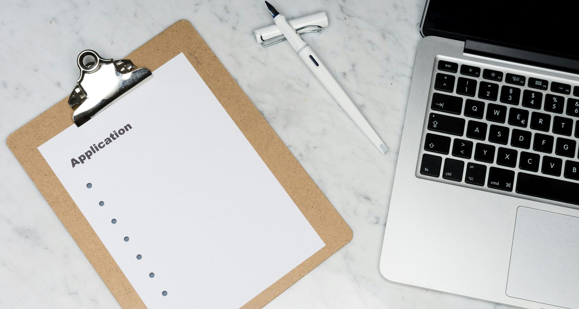 weisses-papier-auf-brauner-mappe-neben-silbernem-laptop-3Rn2EjoAC1g