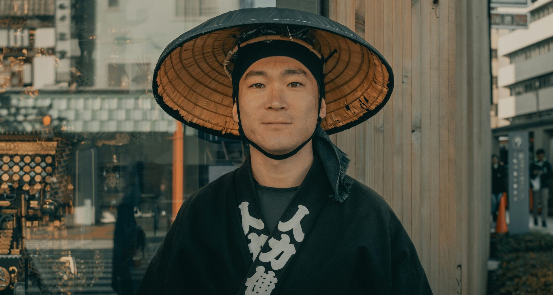 frau-im-schwarzen-mantel-mit-braunem-gewebtem-hut-steht-tagsuber-in-der-nahe-einer-braunen-holzwand-pVpBbIMoDBM