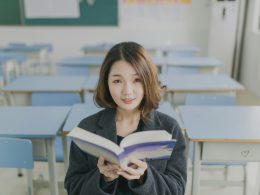frau-die-ein-buch-liest-sitzt-auf-einem-stuhl-im-zimmer-i5nMmbr8JYg