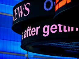 nahaufnahme-eines-schildes-mit-einem-gebaude-im-hintergrund-2oyHDz6LW1w