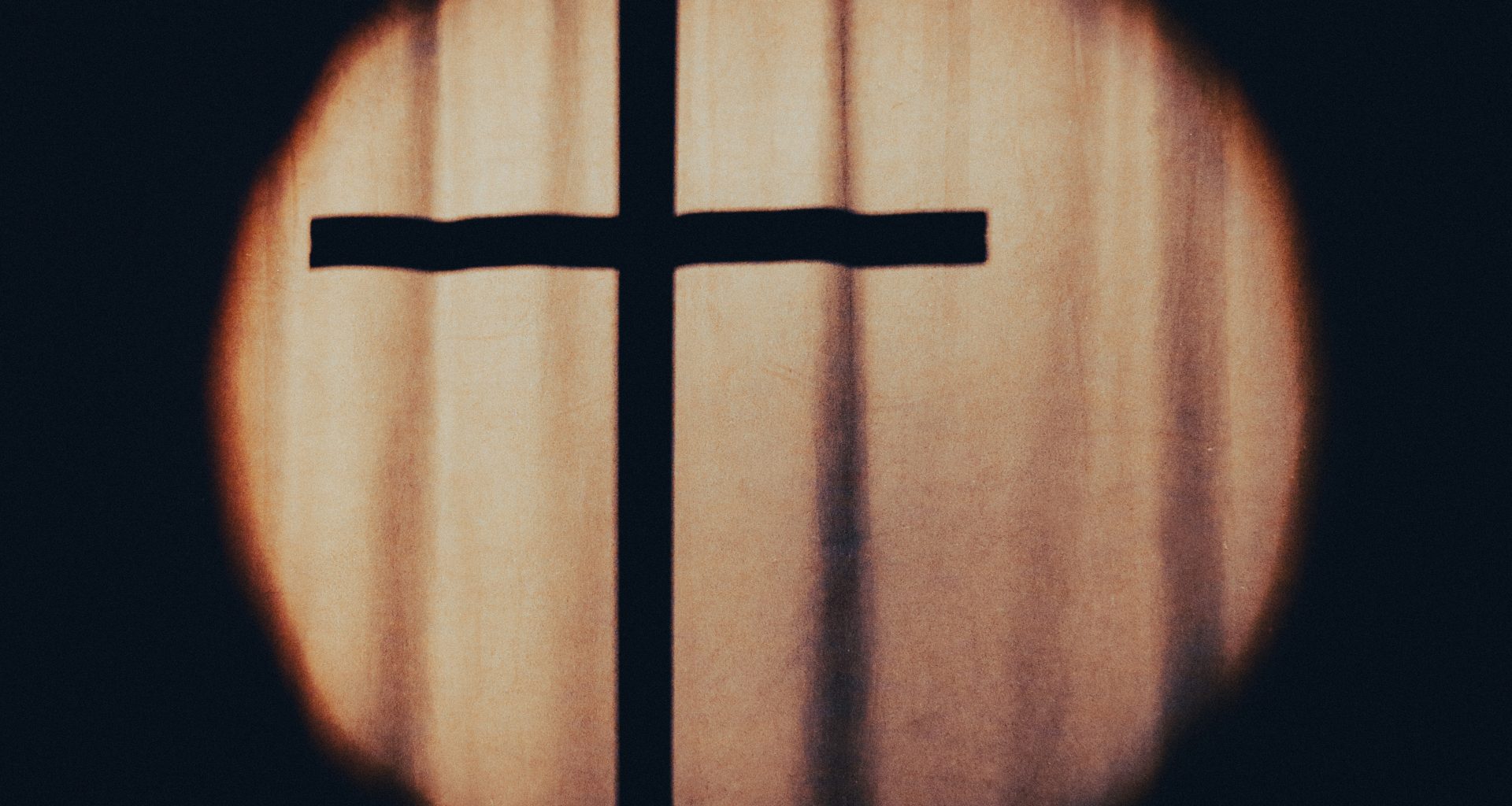 ein-kreuz-ist-durch-ein-rundes-fenster-zu-sehen-j93RfbkK0P4